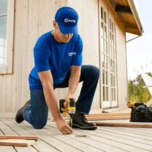 handyman using power drill to repair deck